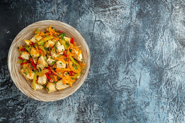 Top view of chicken salad with vegetables on light surface