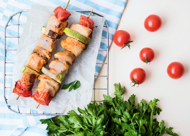 Free Photo top view chicken skewers on parchment paper with cherry tomatoes