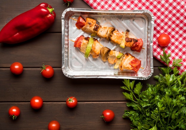 Free photo top view chicken skewers on tray with red pepper and tomatoes