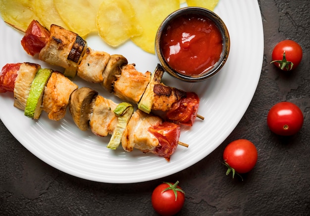 Free photo top view chicken skewers with sauce and chips on plate