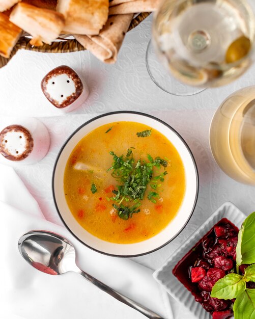 Top view of chicken soup bowl served with feijoa kompot and bread