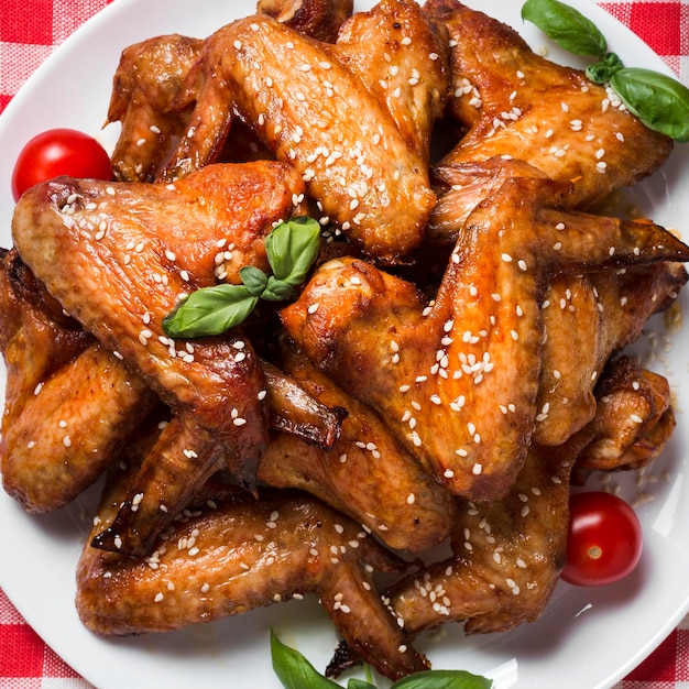 Free photo top view chicken wings on plate with sesame seeds and cherry tomatoes