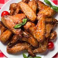 Free photo top view chicken wings on plate with sesame seeds and cherry tomatoes