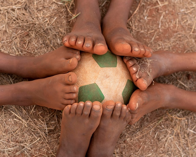 Top view childs feet around football ball