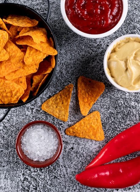 Free Photo top view chips in black metal pan and spices with sauses in bowls on white stone  vertical