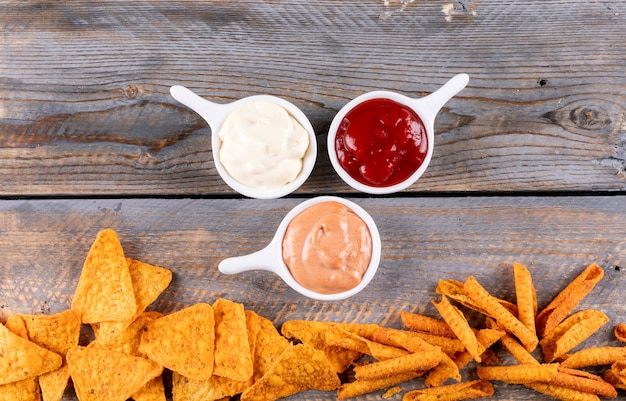 Free Photo top view chips with sauses in bowls on brown wooden