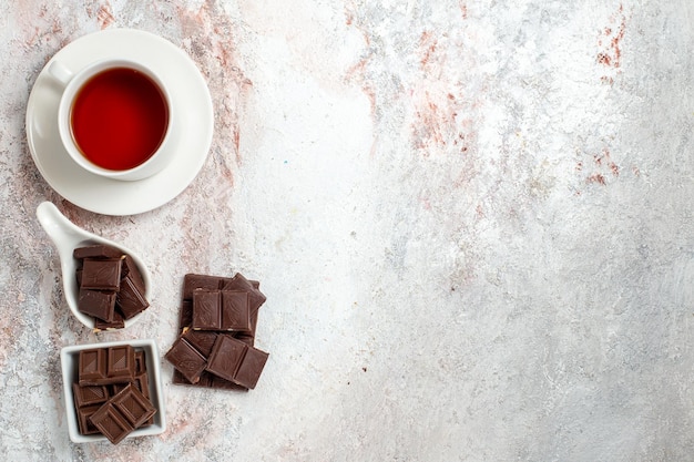 Free photo top view of chocolate bars with cup of tea on white surface