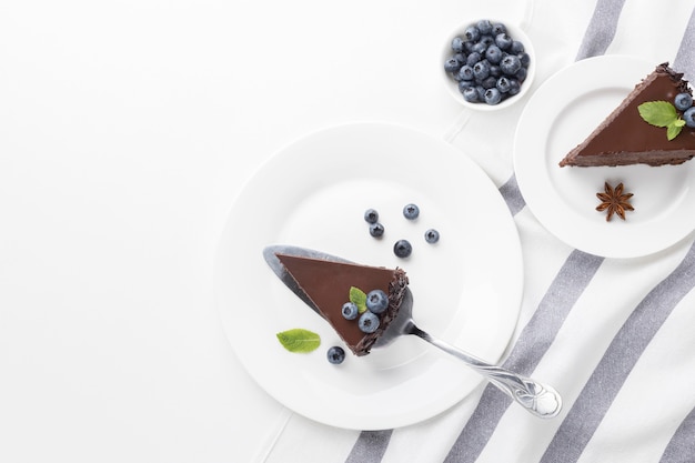 Top view of chocolate cake slices on plates with blueberries