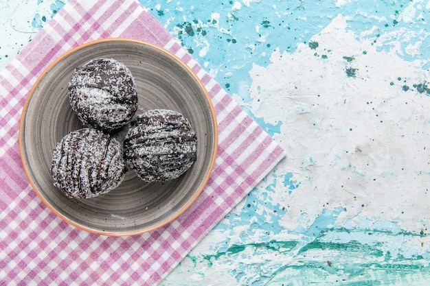 Free photo top view chocolate cakes with icing and sugar powder on light blue background cake chocolate biscuit sugar sweet color