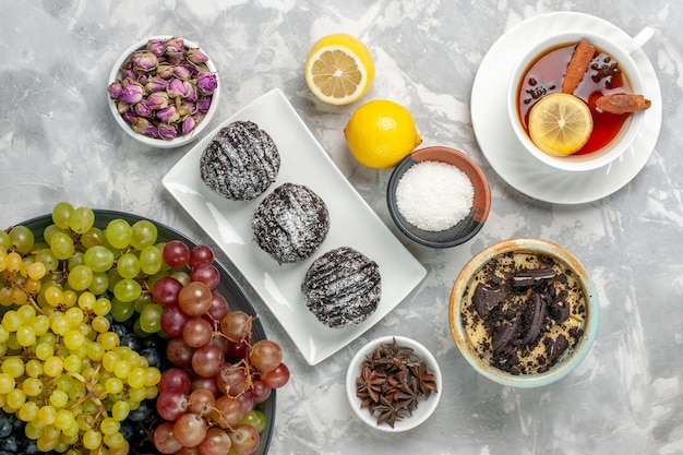 Free photo top view chocolate cakes with lemon grapes and tea on white surface