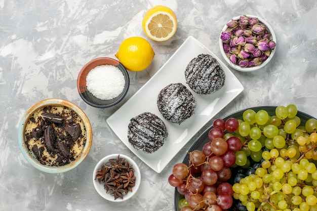 Free photo top view chocolate cakes with lemon and grapes on white surface