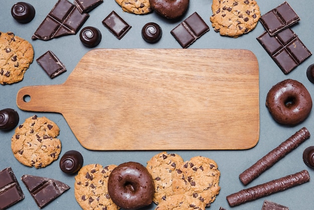 Top view chocolate candies around a cutting board