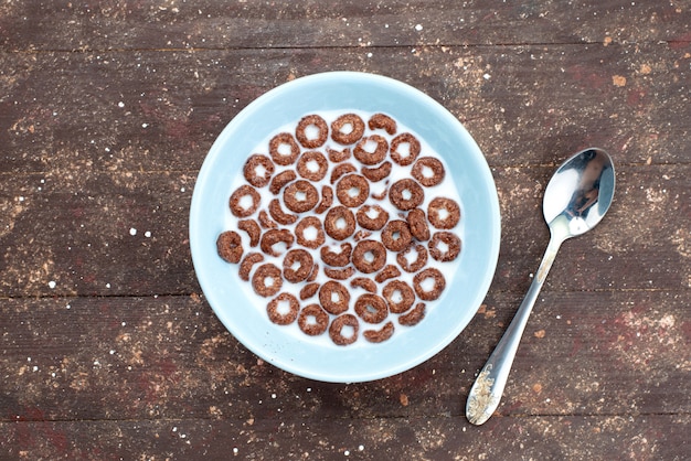 Free Photo top view chocolate cereals with milk inside blue plate and along with spoon on brown