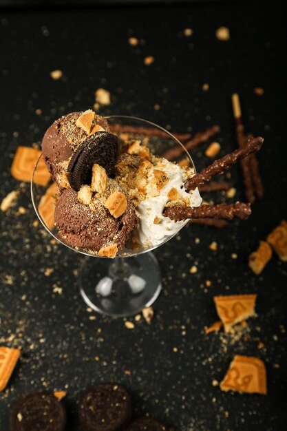 Top view chocolate chip cookies with whipped cream and chocolate sticks in glass on black table