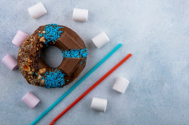 Free Photo top view of chocolate donut with marshmallows and blue with red straws on a gray surface