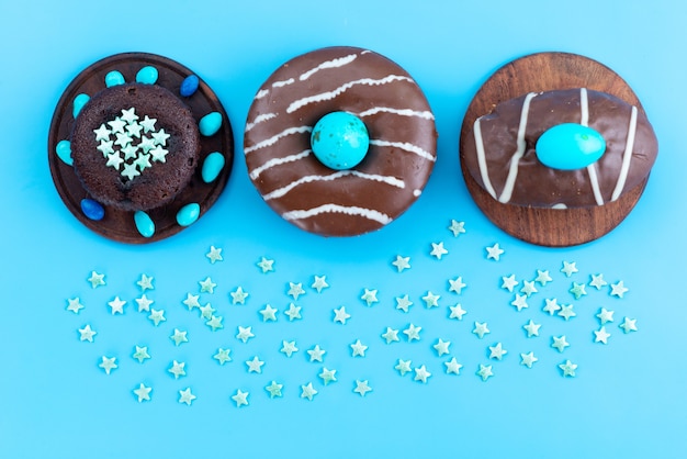 Free photo a top view chocolate donuts with blue candies on blue desk, candy sweet sugar color