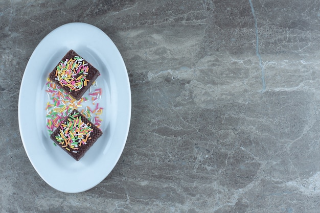 Top view of chocolate wafers with sprinkle on white plate.