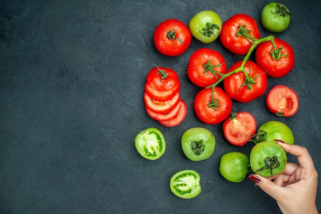 Free photo top view chopped tomatoes tomato branch fresh green tomato in female hand on black table