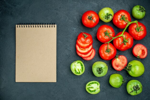 Top view chopped tomatoes tomato branch fresh green tomatoes notepad on black table