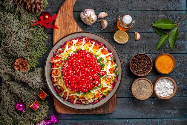 Top view Christmas food on the board plate of Christmas dish on board next to the branches with cones oil bowls of spices garlic lemon