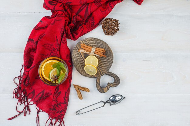 Top view of cinnamon and citrus fruits on wooden board with herbal tea