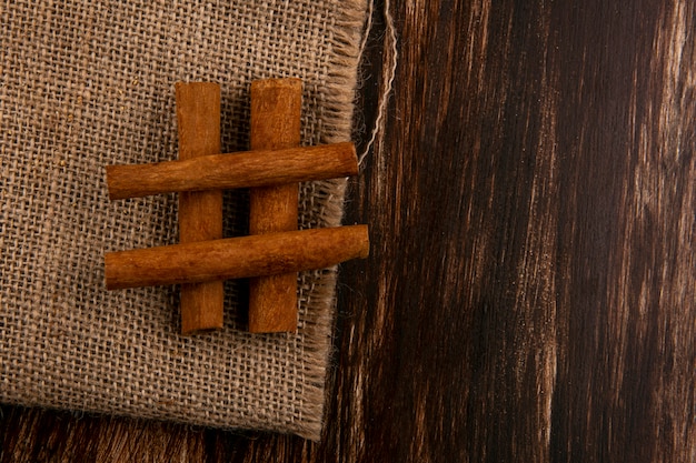 Free Photo top view of cinnamon on sackcloth on wooden background with copy space