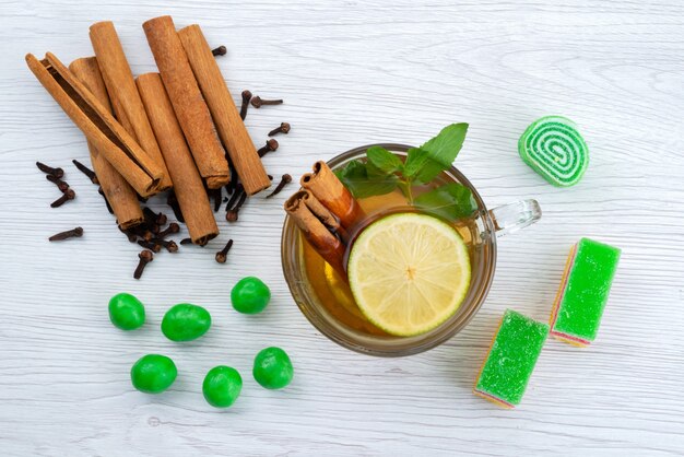 A top view cinnamon and tea with lemon and marmalade on white desk, candy dessert tea