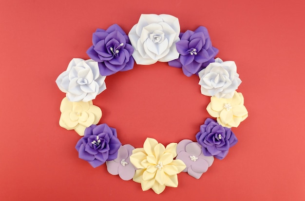 Free photo top view circular frame with paper flowers and red background