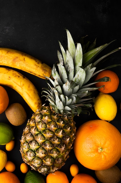 Free Photo top view of citrus fruits as pineapple orange banana and others on black surface