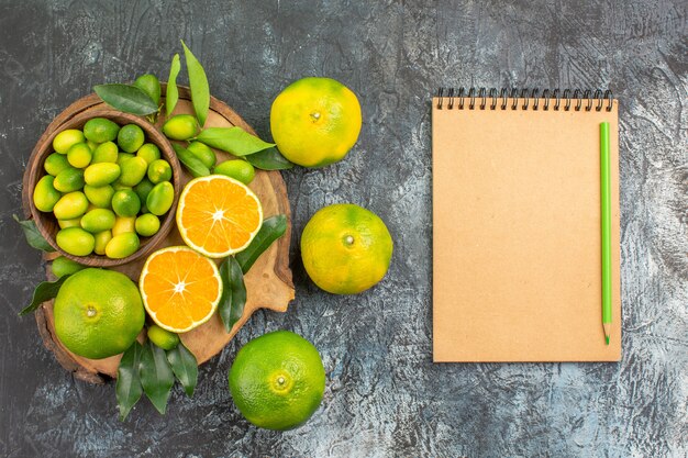 Top view citrus fruits the board with different kinds of citrus fruits notebook pencil