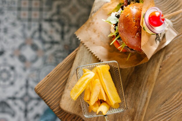 Top view close-up of burger and fries on wooden board