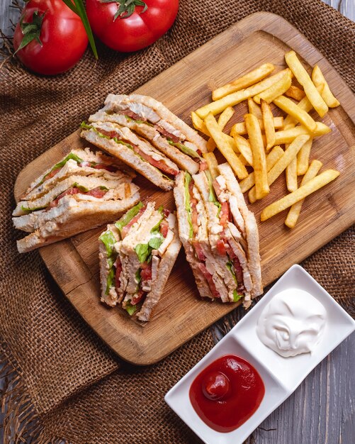 Top view club sandwich with french fries ketchup with mayonnaise and tomatoes