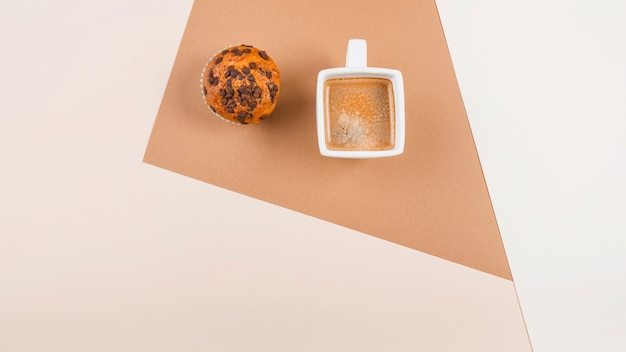 Top view of coffee cup and muffins on colored background