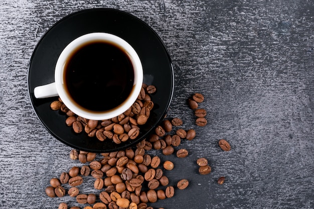 Top view coffee cup with coffee beans on dark table