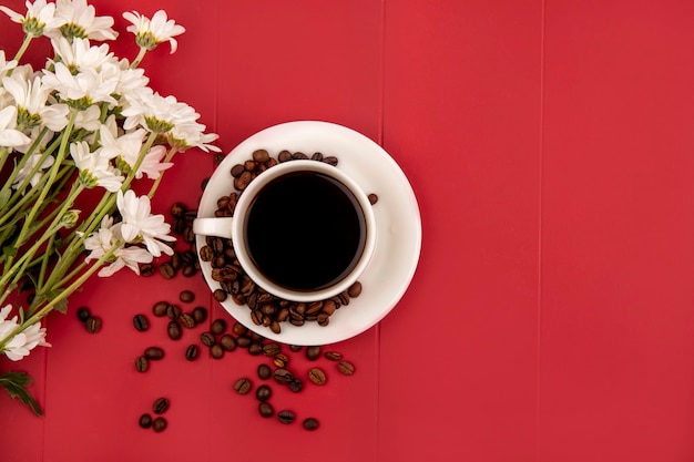 Top view of coffee on a white cup with flowers on a red background with copy space