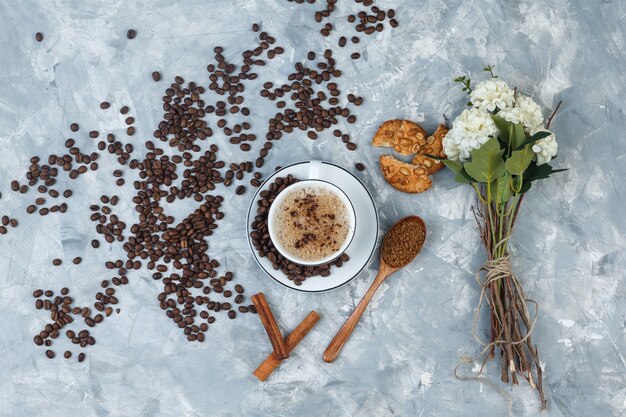 Top view coffee with grinded coffee, coffee beans, flowers, cinnamon sticks, cookies on grungy grey background. horizontal