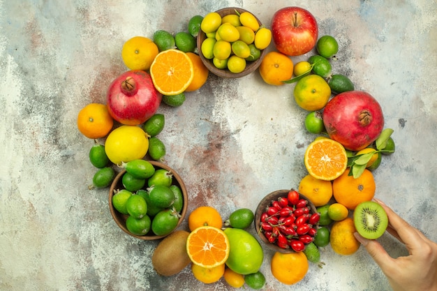 Top view of collection of whole and cut fresh fruits on mixed color background