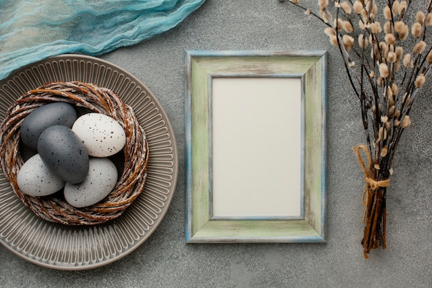 Free photo top view of colored easter eggs in basket with frame and twigs