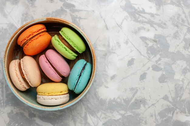 Top view colored french macarons delicious little cakes on the white surface