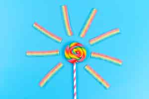 Free photo a top view colored lollipop along with chewing marmalades on blue