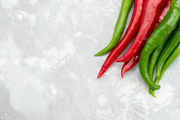 Top view colored spicy peppers green and red on grey desk