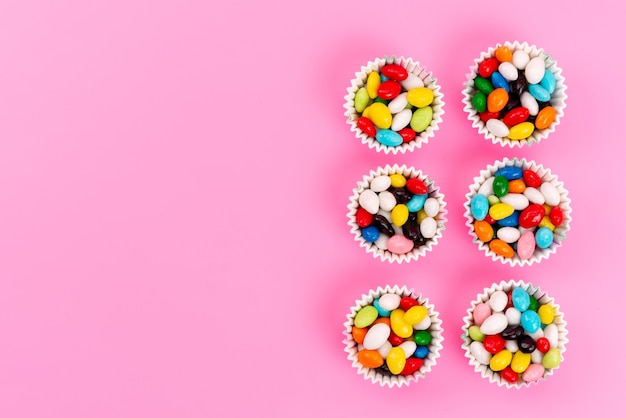 Free photo a top view colorful candies inside paper packages on pink