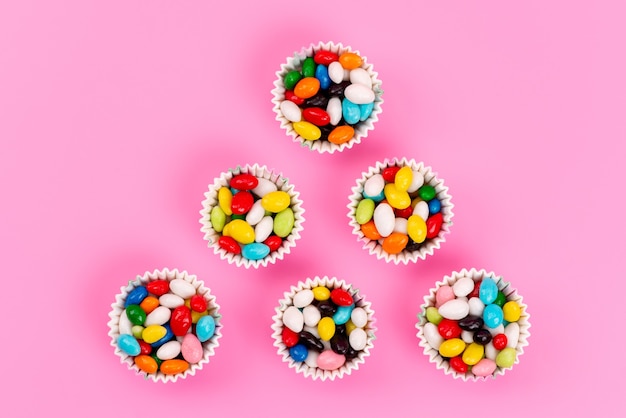 Free photo a top view colorful candies inside paper packages on pink