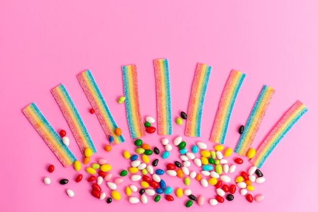 Free photo a top view colorful candies with rainbow marmalades on pink desk, sweet sugar rainbow