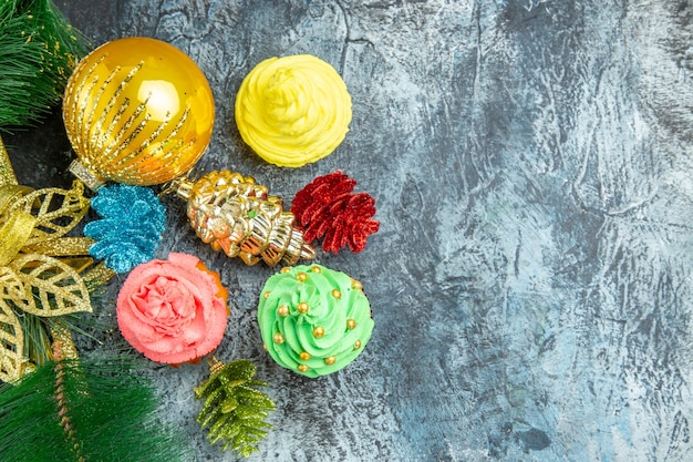 Top view colorful cupcakes xmas ornaments on grey background