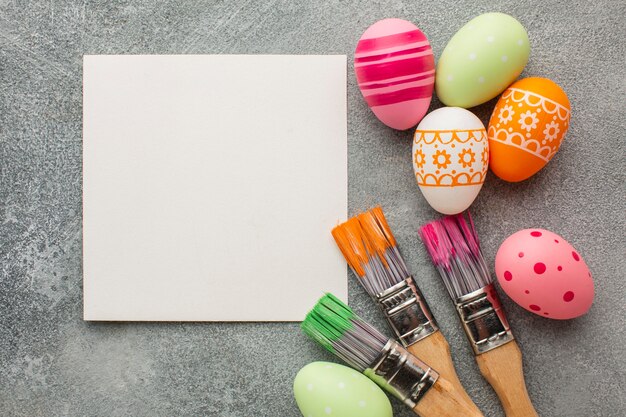 Top view of colorful easter eggs with paint brushes and paper