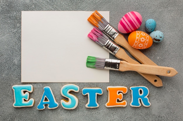 Top view of colorful easter eggs with paint brushes and paper