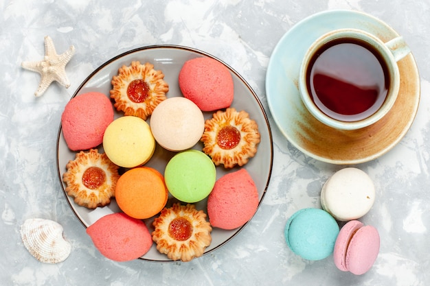 Top view colorful french macarons delicious cakes with cookies and tea on white surface bake cake sweet sugar dessert biscuit