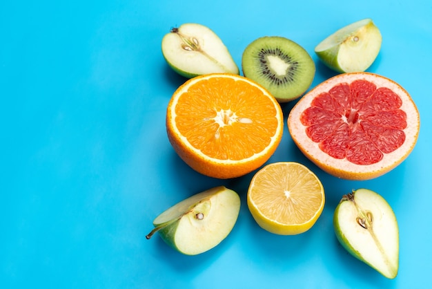 A top view colorful fruits composition sliced mellow and fresh fruits on blue, fruit color image