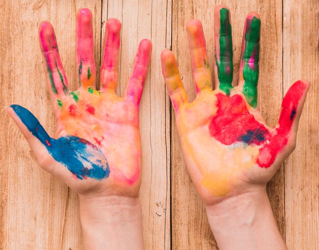 Top view of a colorful painted hand hands on wooden desk